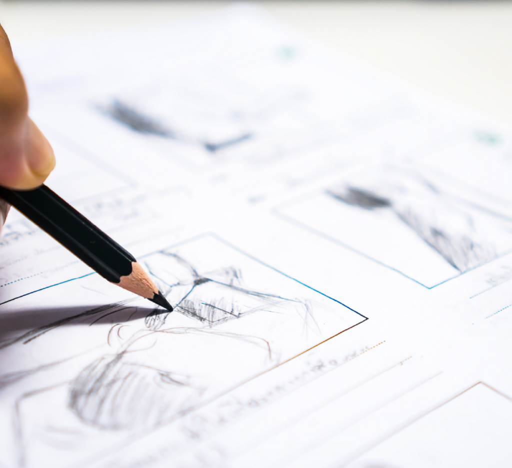 Close-up of a hand drawing storyboard sketches with a pencil on paper.