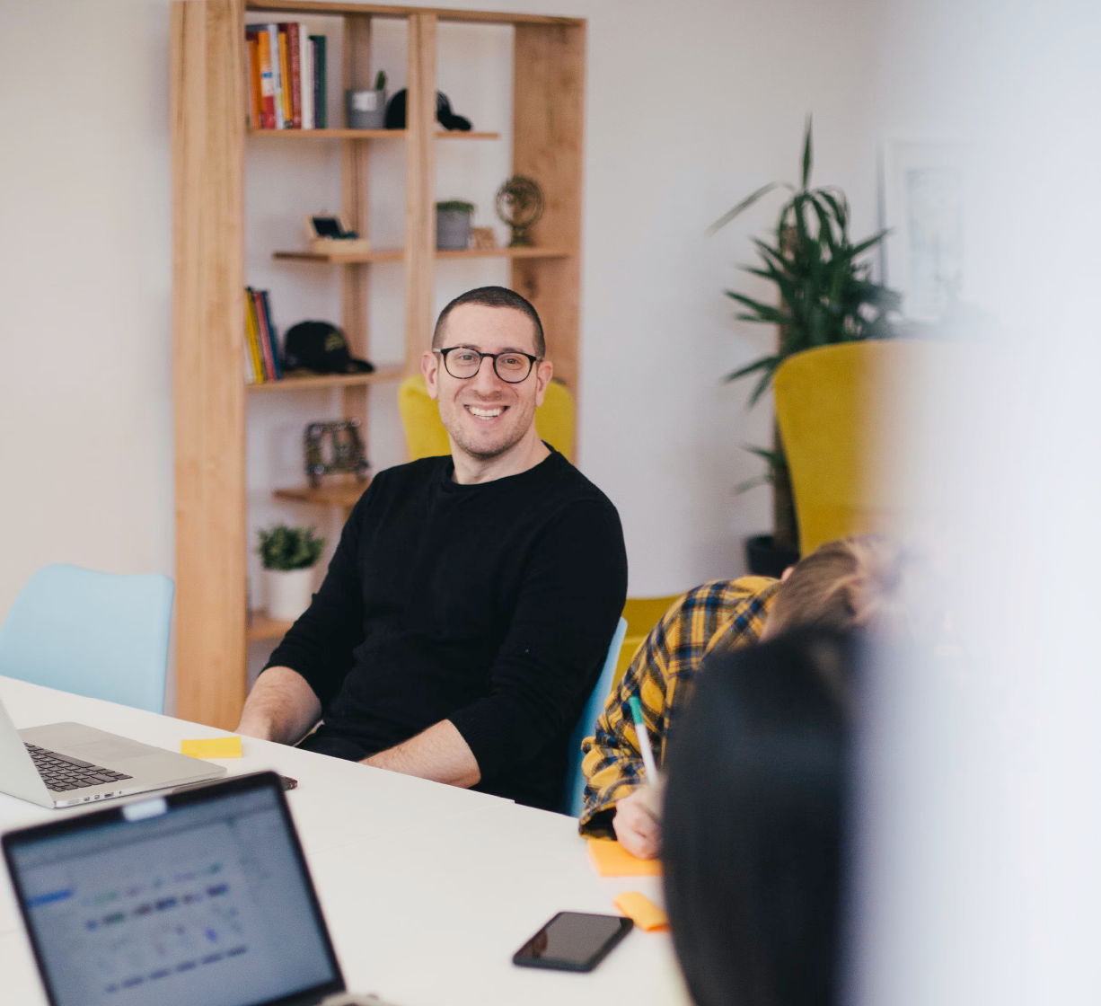 Man smiling during a team meeting in a modern office.