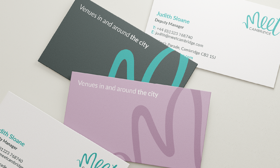 A set of Meet Cambridge business cards arranged on a surface, featuring brand colours and the line “Venues in and around the city.”