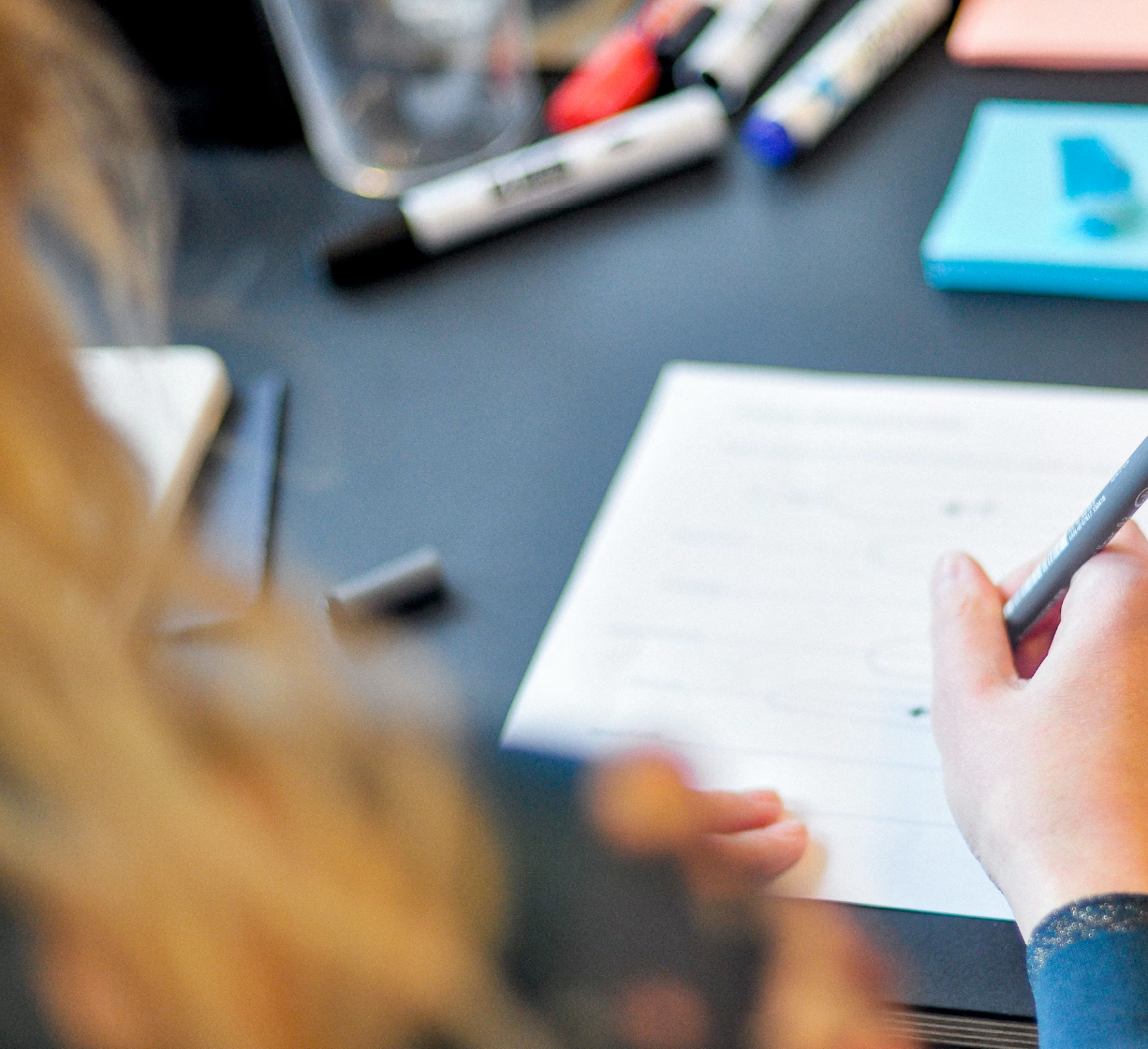 Person writing notes on paper at a desk as part of a workshop