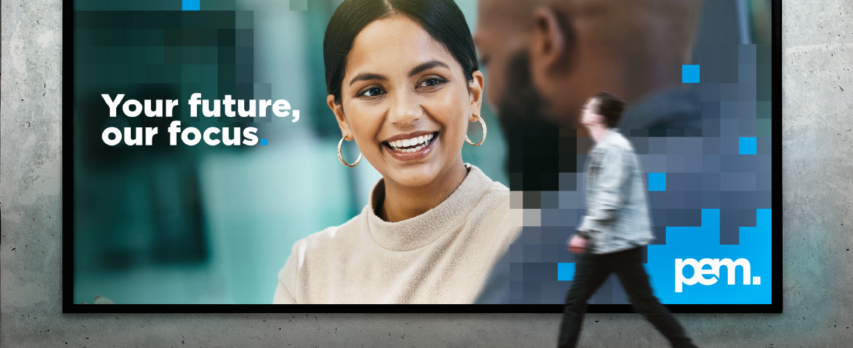 Large billboard with the text “Your future, our focus” and a pixel-style graphic design, with a person walking past and the pem. logo in the corner.