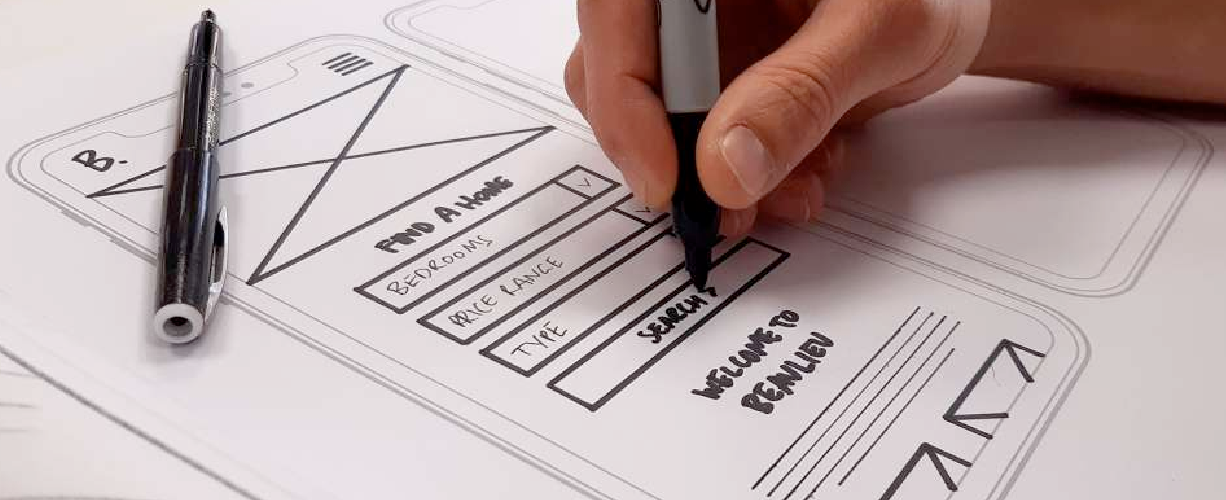 Hand sketching a mobile app wireframe layout with form fields and navigation elements on paper.