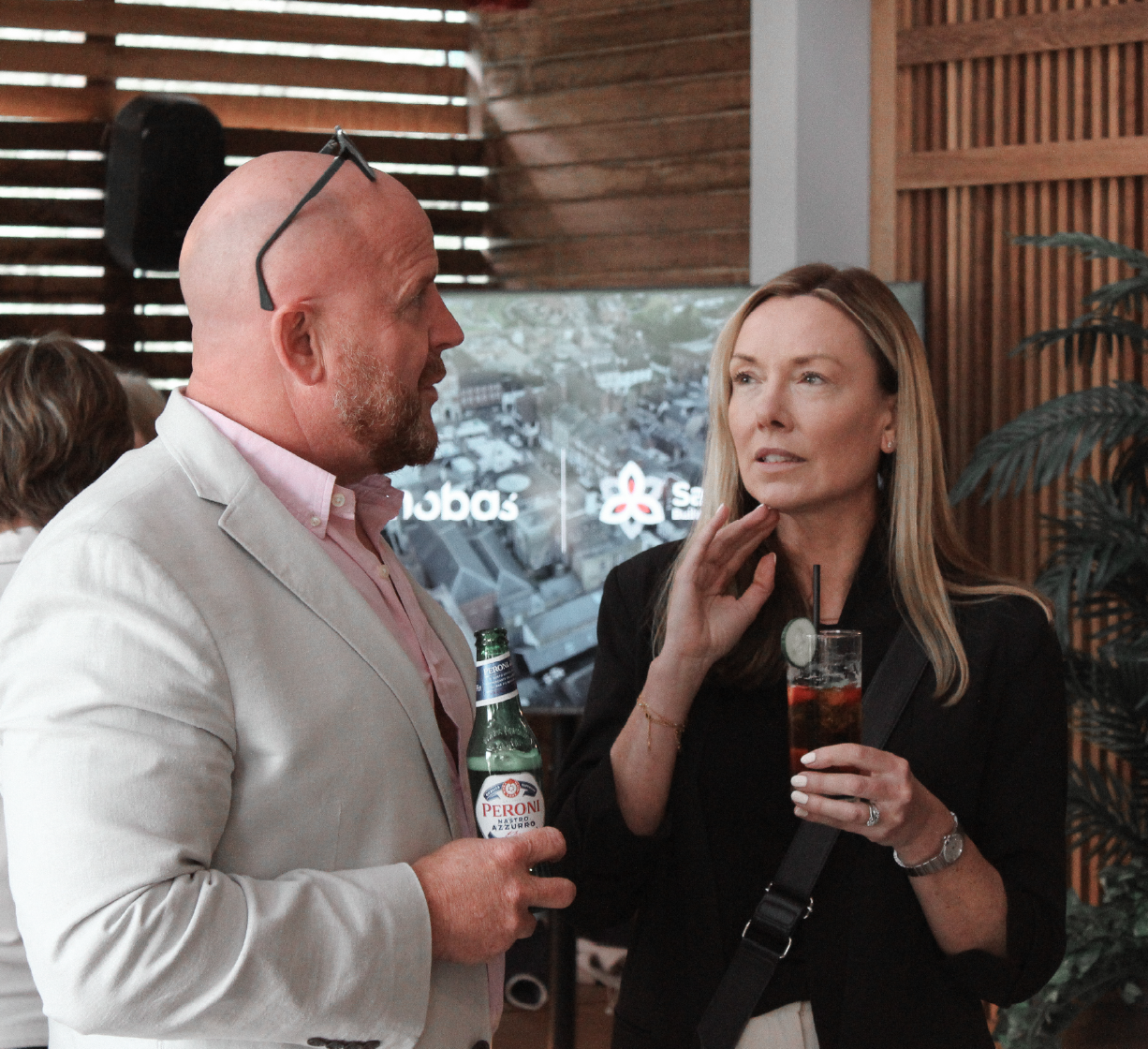 Two people chatting and holding drinks at a networking event.