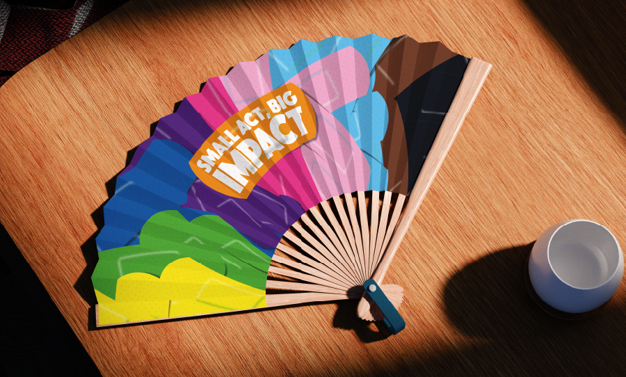 Colorful hand fan on a desk with the text ‘Small act, big impact.’