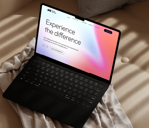 Laptop displaying the White & Black website homepage with the headline ‘Experience the difference’ on a modern, minimalist workspace.