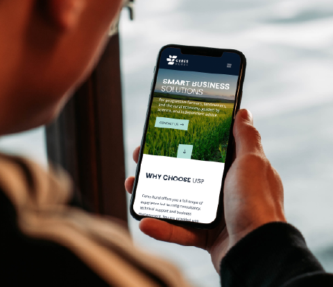 Person holding a smartphone displaying the Ceres Rural mobile website homepage.